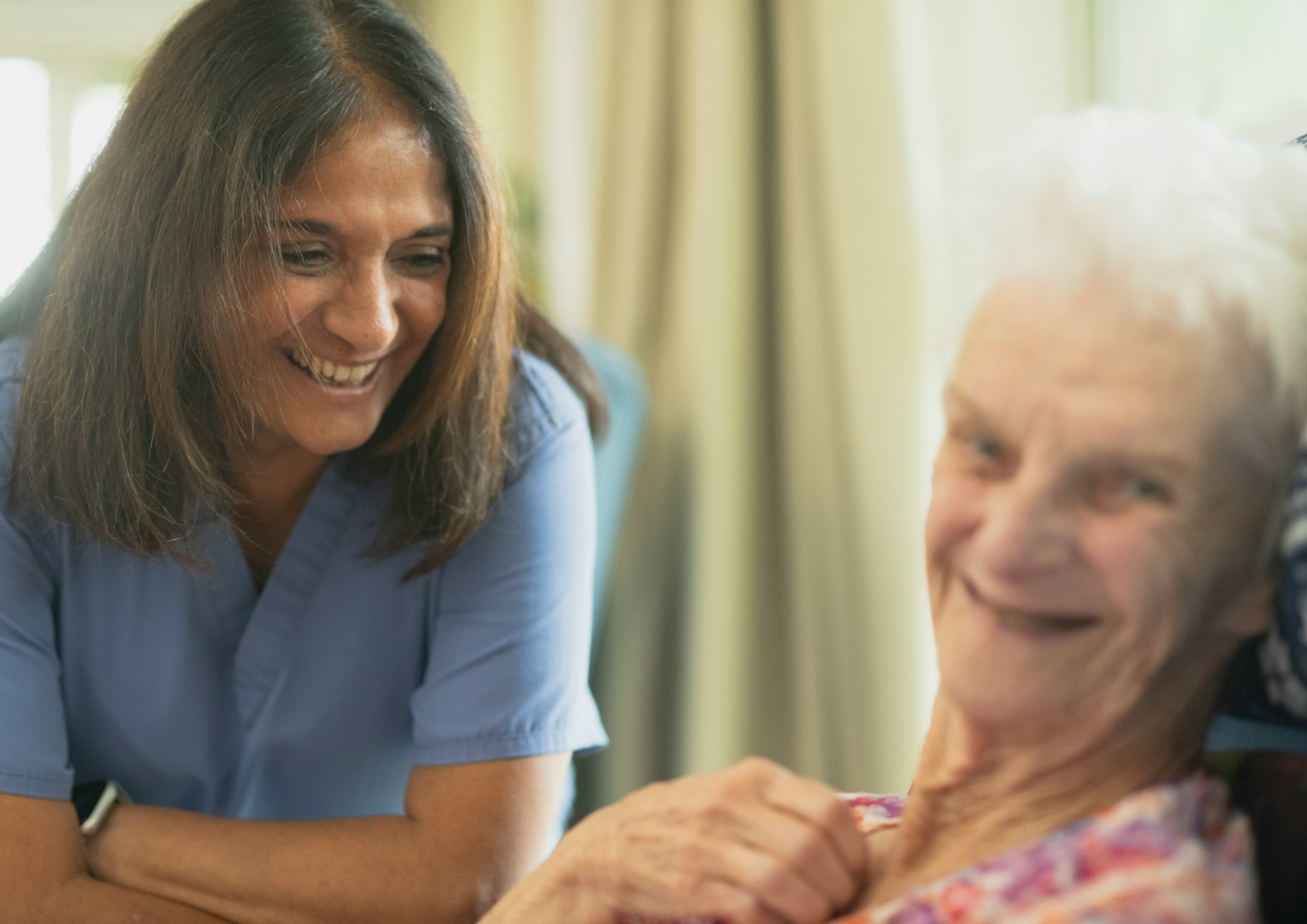 Caregiver providing attentive support to an elderly woman at home
